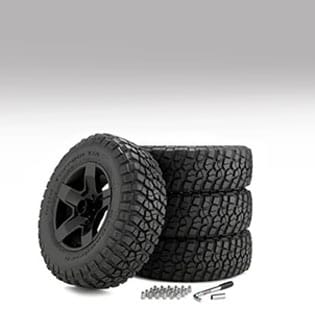 Stack of off-road tires with bolts and wrench.