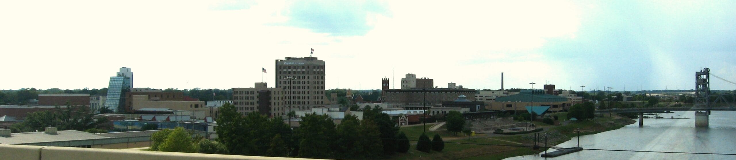Skyline of a city with a riverside bridge.