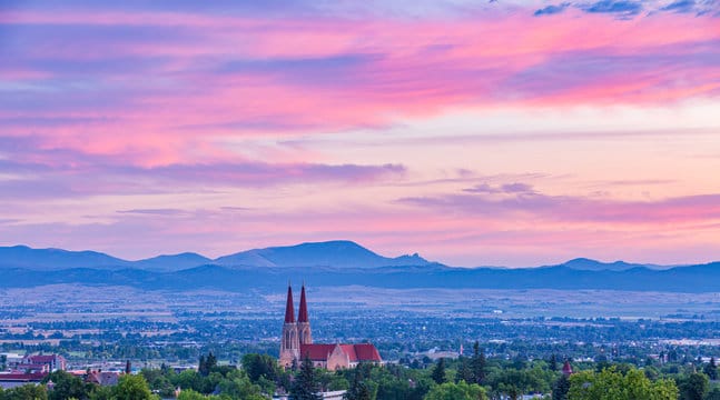 Cathedral against a vibrant sunset and mountains.