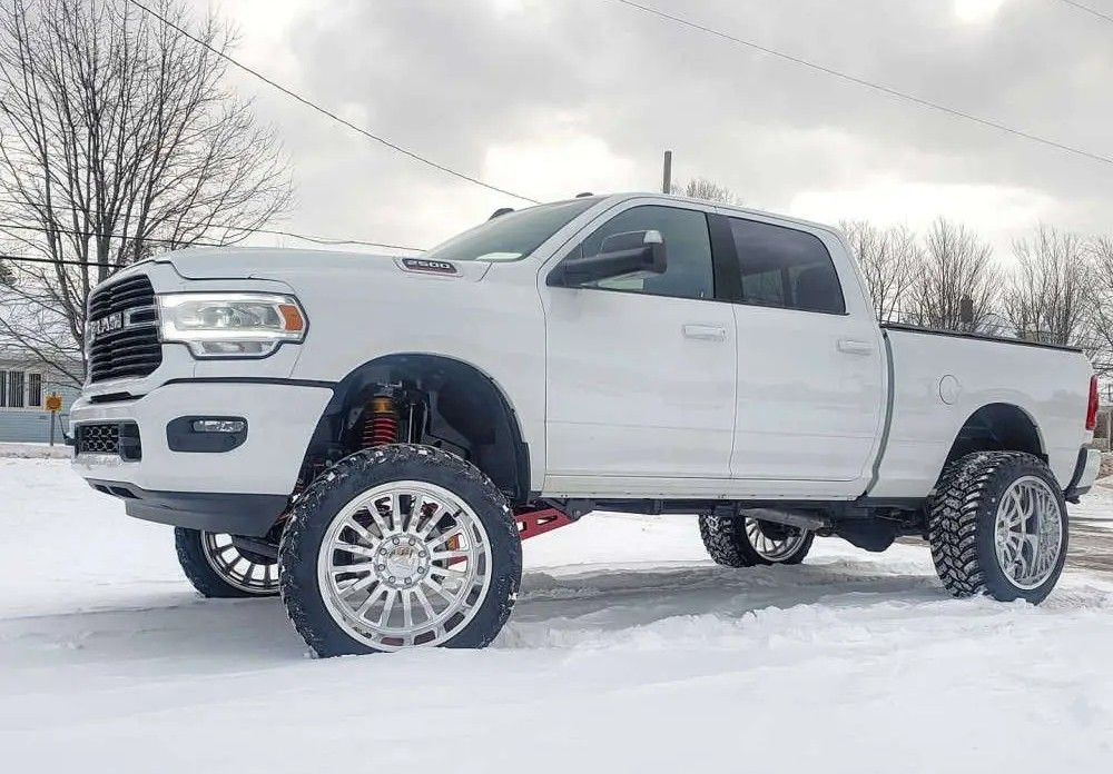 Lifted white truck on snowy terrain - chrome wheel and tire packages