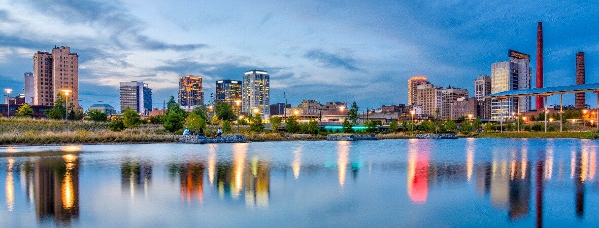 City skyline reflecting on calm water at dusk.