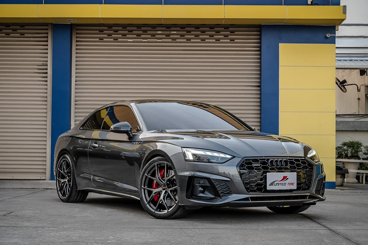 Sleek gray sports car in front of garage.