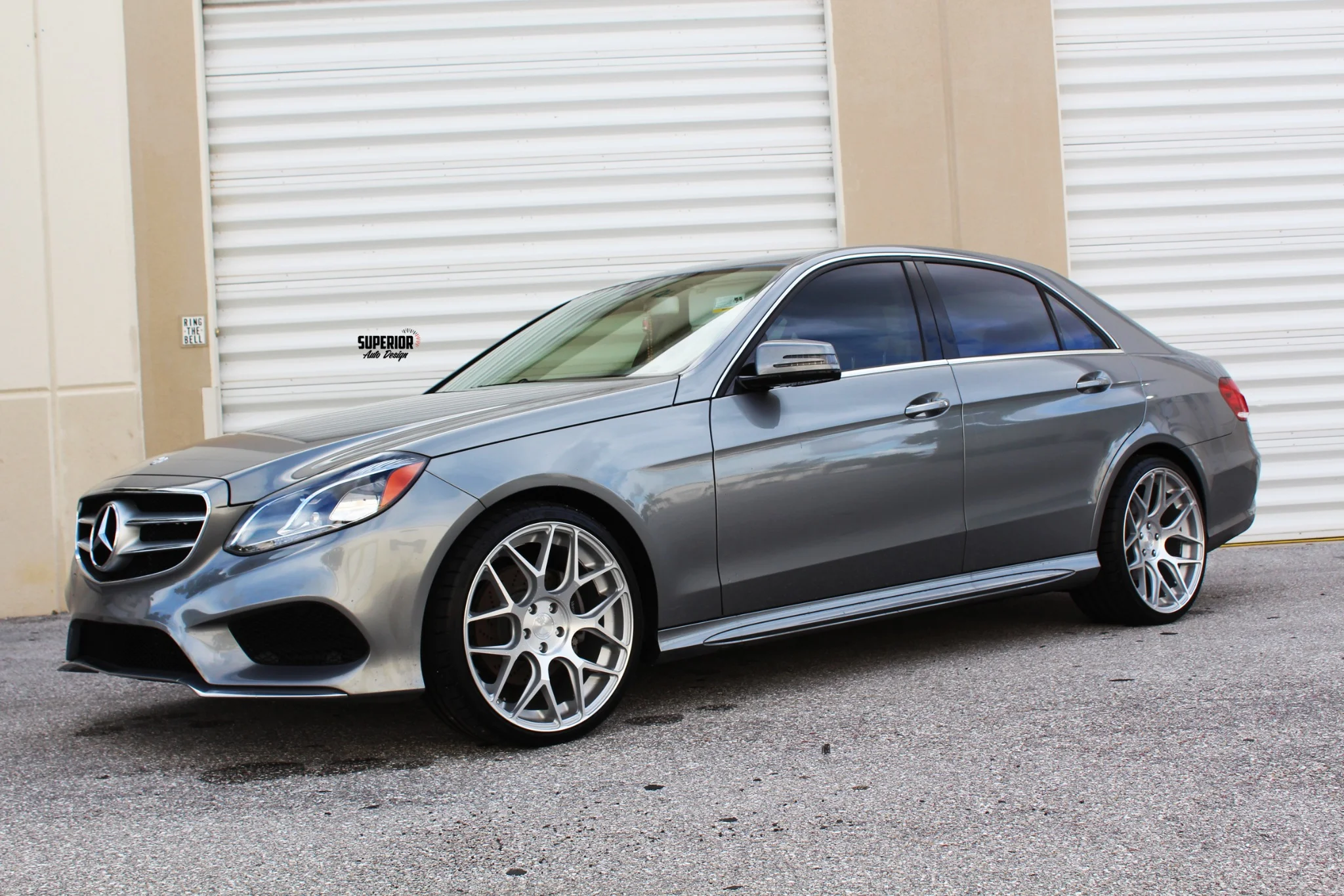 Luxury silver sedan parked near warehouse doors.